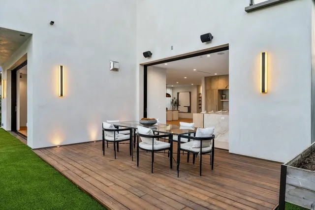 Modern patio with wooden deck, outdoor dining table and chairs.